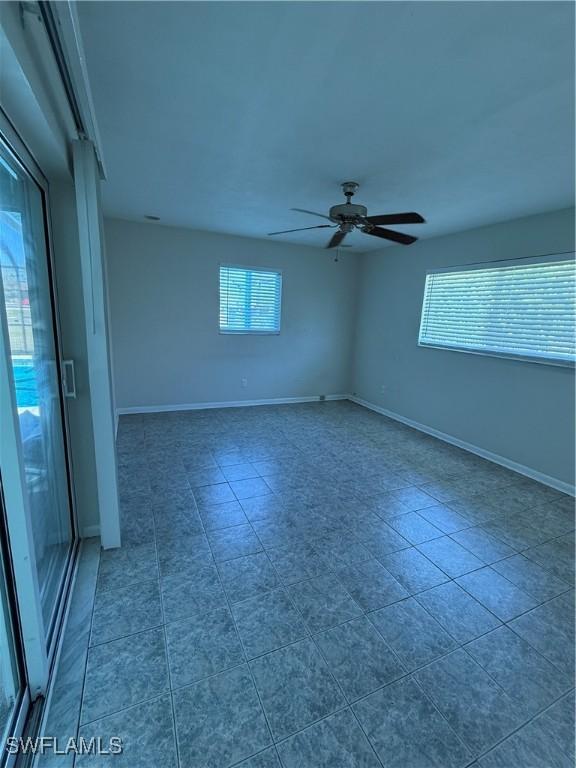 empty room with a ceiling fan and baseboards