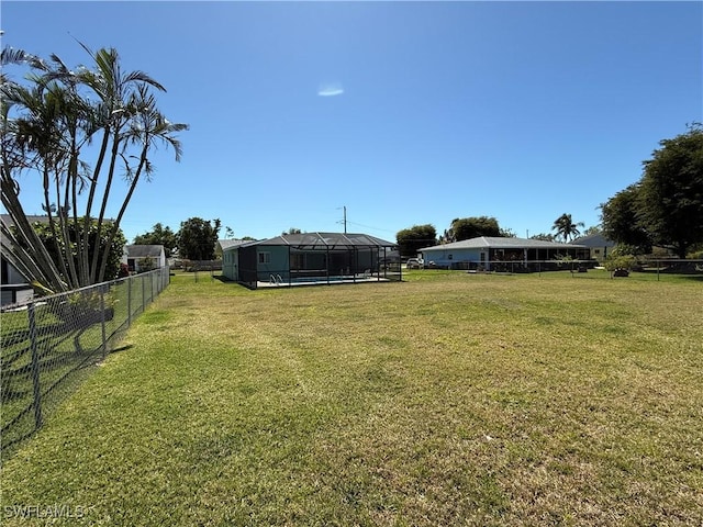 view of yard featuring glass enclosure and fence