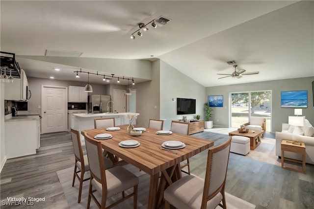 dining space with visible vents, wood finished floors, ceiling fan, and vaulted ceiling