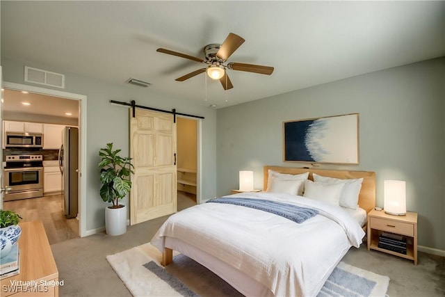 bedroom featuring a barn door, visible vents, freestanding refrigerator, and light carpet