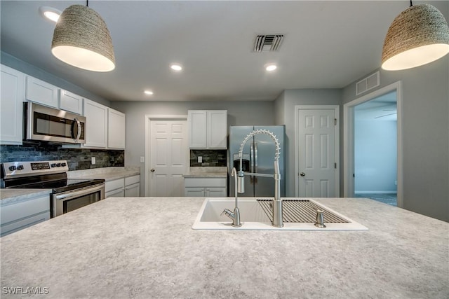 kitchen featuring visible vents, appliances with stainless steel finishes, decorative backsplash, and a sink