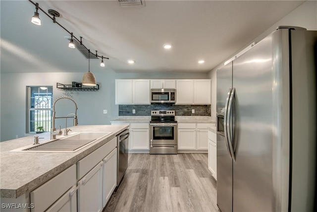 kitchen with light wood-style flooring, a sink, backsplash, white cabinetry, and stainless steel appliances