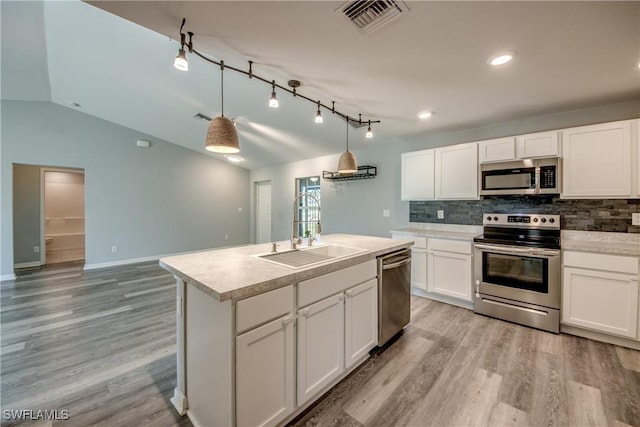 kitchen with visible vents, light wood-style flooring, a sink, decorative backsplash, and appliances with stainless steel finishes