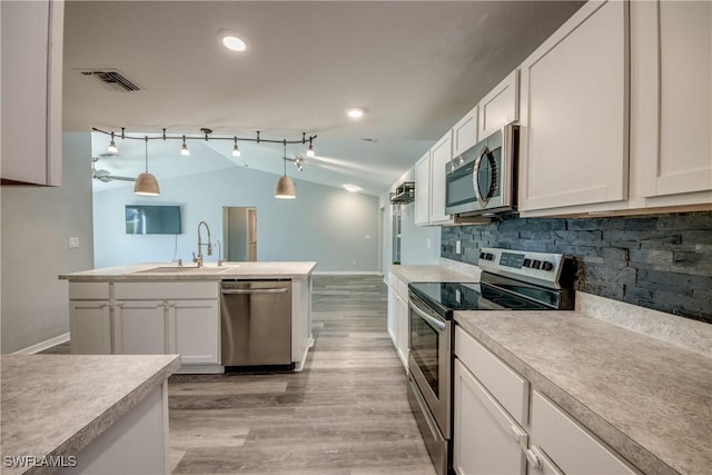 kitchen featuring visible vents, a sink, vaulted ceiling, light countertops, and appliances with stainless steel finishes