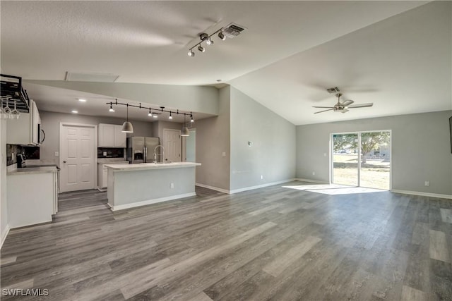 unfurnished living room featuring visible vents, dark wood finished floors, a ceiling fan, and vaulted ceiling