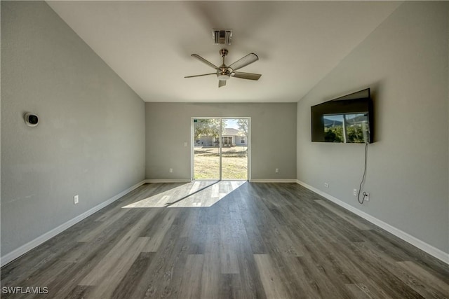 spare room with vaulted ceiling, visible vents, baseboards, and wood finished floors