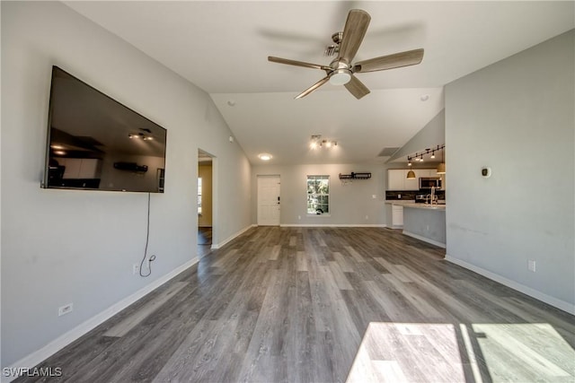 unfurnished living room featuring a ceiling fan, vaulted ceiling, wood finished floors, and baseboards