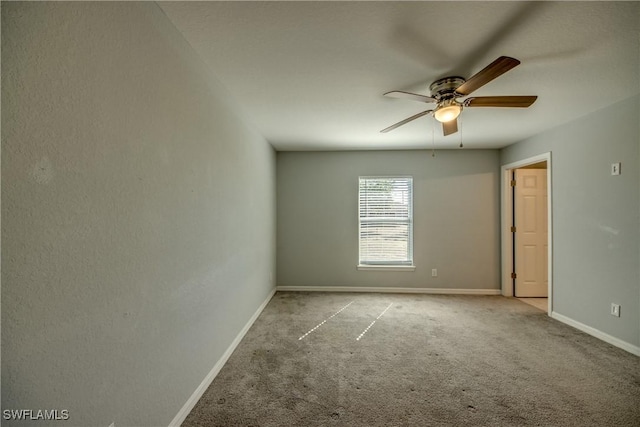 carpeted empty room featuring a ceiling fan and baseboards