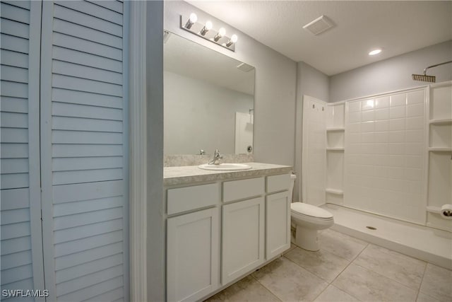 bathroom featuring visible vents, toilet, a tile shower, tile patterned floors, and vanity