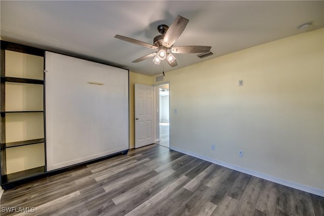 unfurnished bedroom with ceiling fan, wood finished floors, visible vents, and baseboards