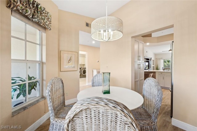 dining space featuring wood finished floors, baseboards, washer / clothes dryer, recessed lighting, and a notable chandelier