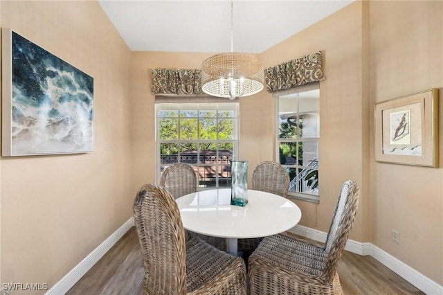 dining space featuring baseboards, an inviting chandelier, and wood finished floors