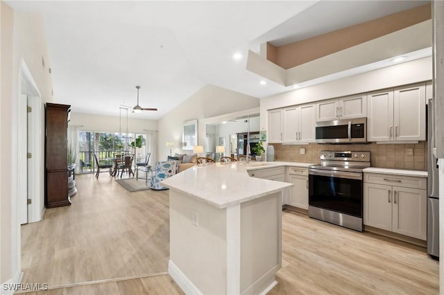 kitchen featuring stainless steel appliances, a peninsula, light wood finished floors, decorative backsplash, and lofted ceiling