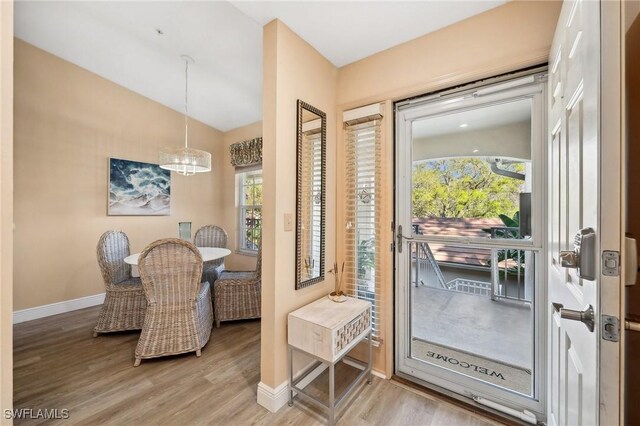 foyer with vaulted ceiling, light wood-style floors, and baseboards