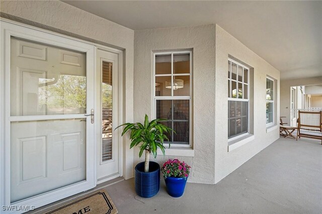 view of exterior entry with covered porch and stucco siding