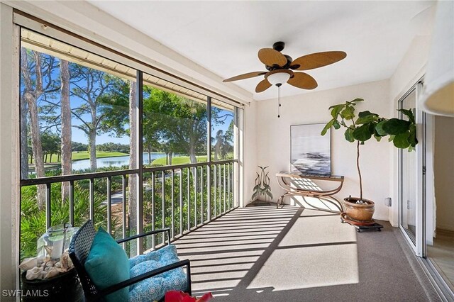 sunroom featuring a ceiling fan and a water view