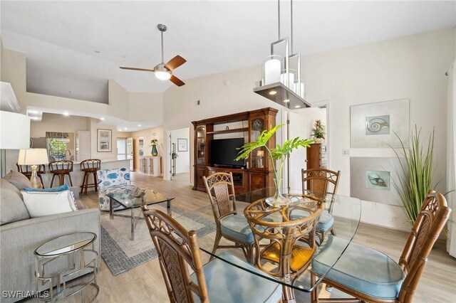 dining area featuring high vaulted ceiling, a ceiling fan, and light wood-style floors