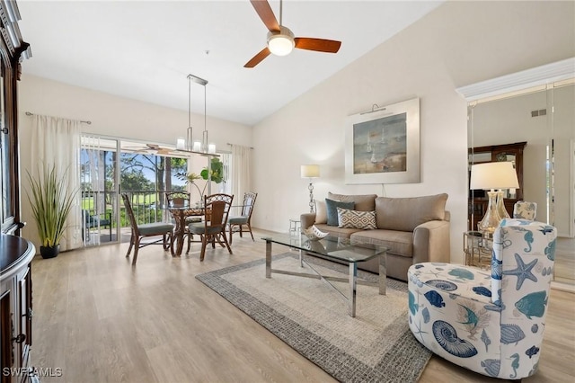 living area with visible vents, ceiling fan with notable chandelier, wood finished floors, and vaulted ceiling