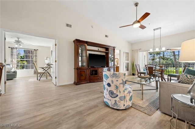 living area featuring light wood-type flooring, visible vents, high vaulted ceiling, and ceiling fan with notable chandelier