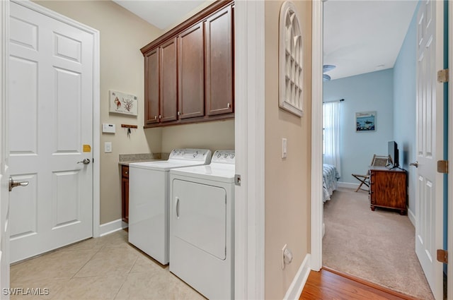 laundry area with light tile patterned floors, baseboards, cabinet space, and washing machine and dryer