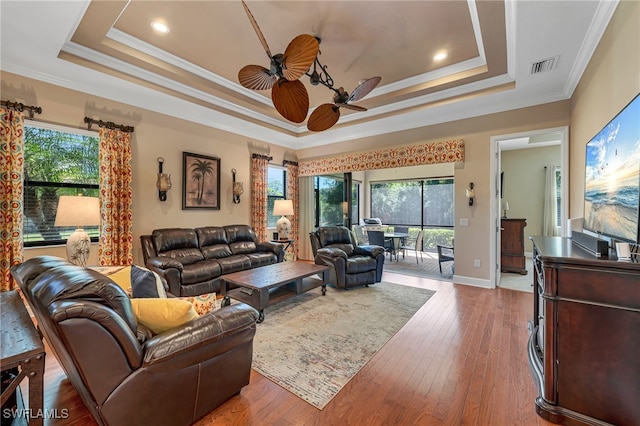 living area featuring a tray ceiling, visible vents, a wealth of natural light, and ceiling fan