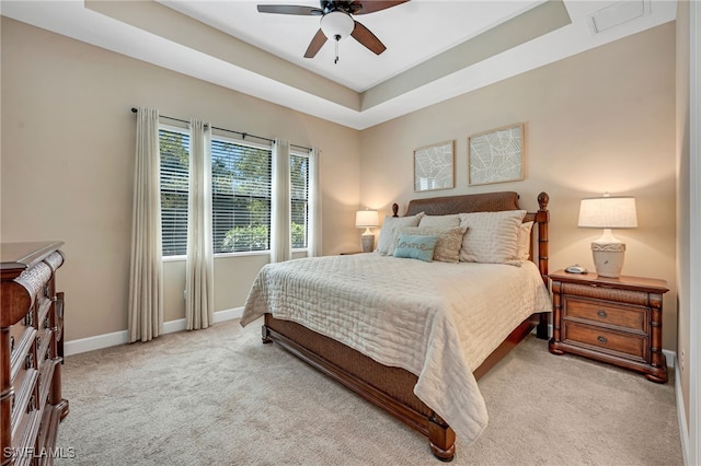 carpeted bedroom featuring ceiling fan, baseboards, and a tray ceiling