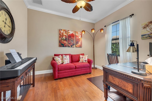 living area with wood finished floors, baseboards, a ceiling fan, visible vents, and ornamental molding