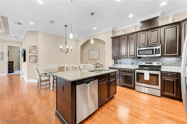 9149 Isla Bella Cir, Bonita Springs, FL 34135 - kitchen featuring stainless steel appliances, a sink, tasteful backsplash, a center island with sink, and light wood-style floors