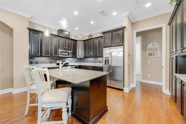 9149 Isla Bella Cir, Bonita Springs, FL 34135 - kitchen with stainless steel appliances, decorative backsplash, an island with sink, ornamental molding, and a breakfast bar