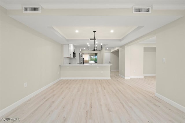 200 Periwinkle Way Unit 132, Sanibel, FL 33957 - unfurnished living room featuring an inviting chandelier, light wood-type flooring, a tray ceiling, and visible vents