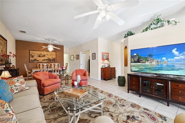 living area featuring light tile patterned floors, visible vents, arched walkways, and ceiling fan