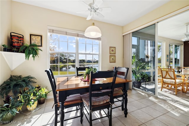 dining room featuring light tile patterned floors, plenty of natural light, ceiling fan, and a water view