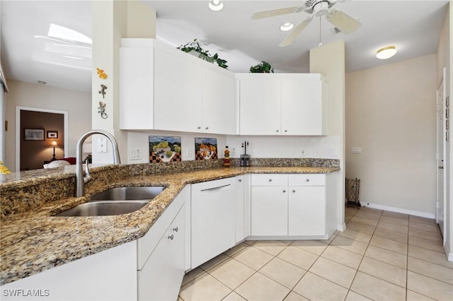 kitchen with a sink, light stone counters, white cabinetry, light tile patterned flooring, and ceiling fan