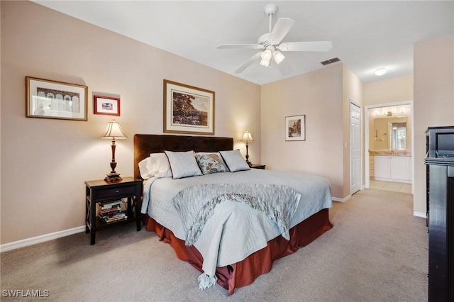 bedroom with visible vents, baseboards, light colored carpet, and ensuite bath