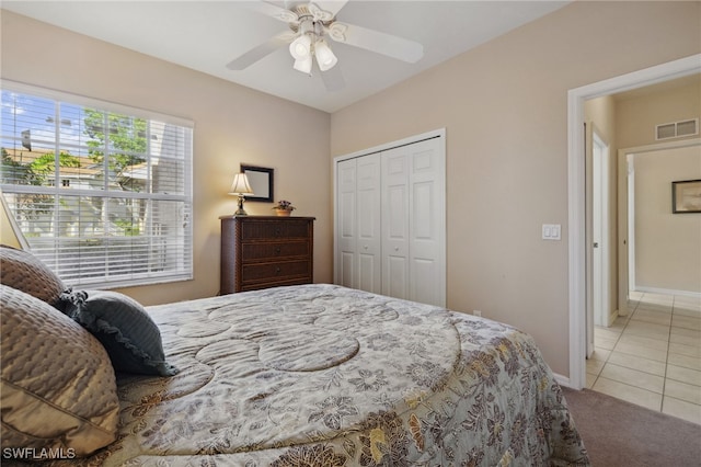 bedroom with visible vents, baseboards, light colored carpet, a closet, and a ceiling fan