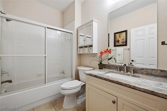 bathroom with combined bath / shower with glass door, toilet, vanity, and tile patterned flooring