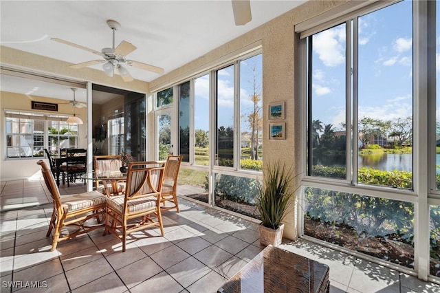 sunroom featuring a ceiling fan and a water view