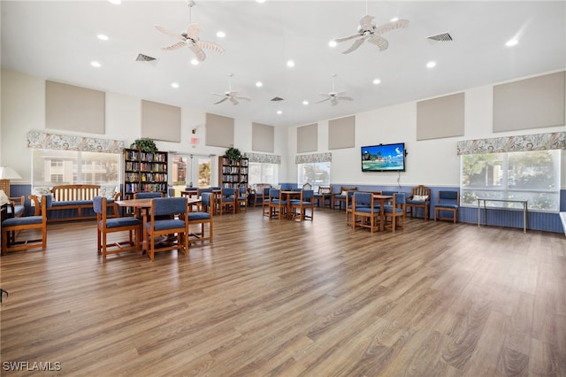 dining area with visible vents, wood finished floors, a ceiling fan, and a towering ceiling