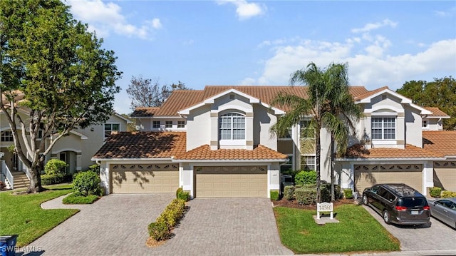 view of front of home featuring a tile roof, a front yard, stucco siding, decorative driveway, and a garage