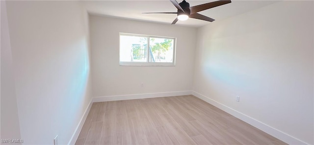 spare room featuring baseboards, light wood finished floors, and ceiling fan