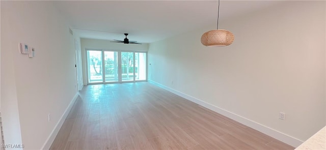 spare room featuring baseboards, light wood-type flooring, and ceiling fan