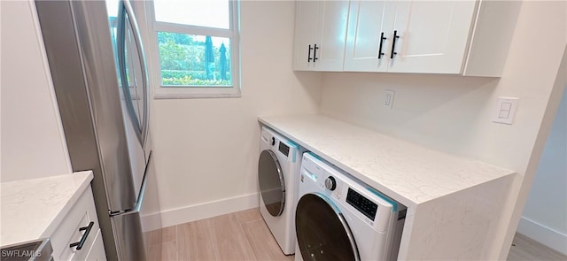 laundry area featuring washing machine and dryer, cabinet space, and baseboards