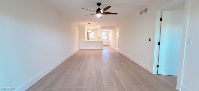 hall with visible vents, baseboards, and light wood-style floors