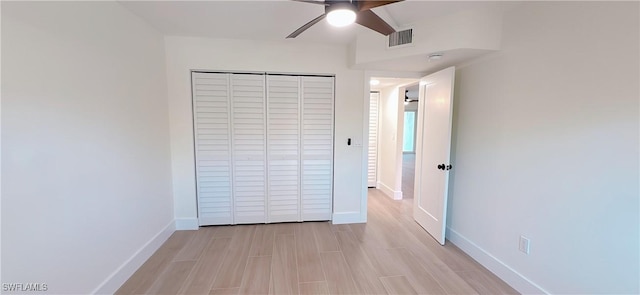 unfurnished bedroom with baseboards, visible vents, light wood finished floors, ceiling fan, and a closet