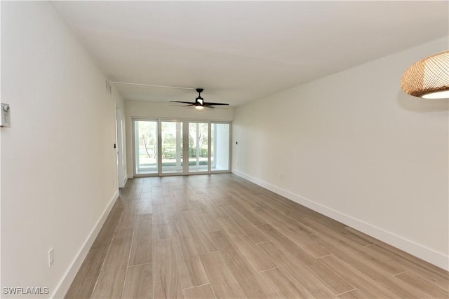 empty room featuring light wood-style flooring, baseboards, and ceiling fan