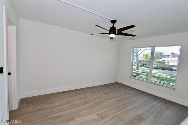 spare room featuring wood finish floors, baseboards, and a ceiling fan