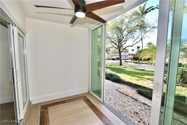 entryway featuring baseboards, a ceiling fan, and a sunroom