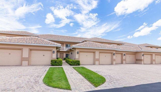 townhome / multi-family property with a balcony, decorative driveway, and stucco siding