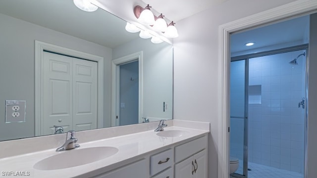 full bath featuring double vanity, tiled shower, toilet, and a sink