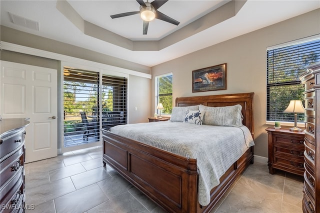 bedroom with baseboards, visible vents, ceiling fan, a raised ceiling, and access to outside